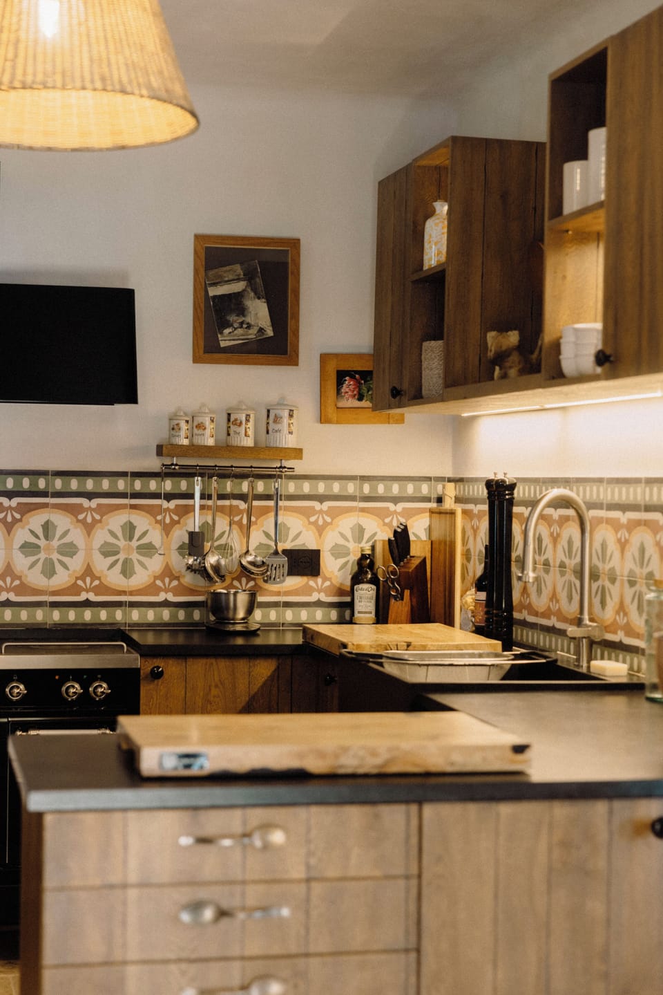 Fully equipped kitchen with Puglian mosaic backsplash and wooden cutting board.