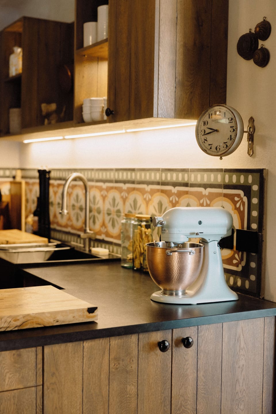 Kitchen with a retro clock, KitchenAid stand mixer, and a stylish bronze bowl.