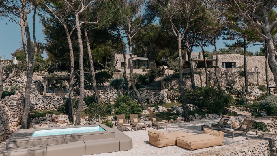Outdoor lounge terrace with sea view, pine trees and elegant wooden seating.