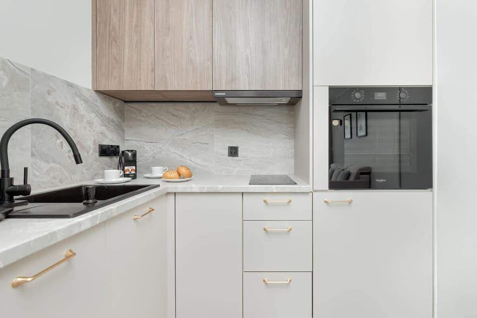 A compact kitchen with white cabinetry and light wood accents.

