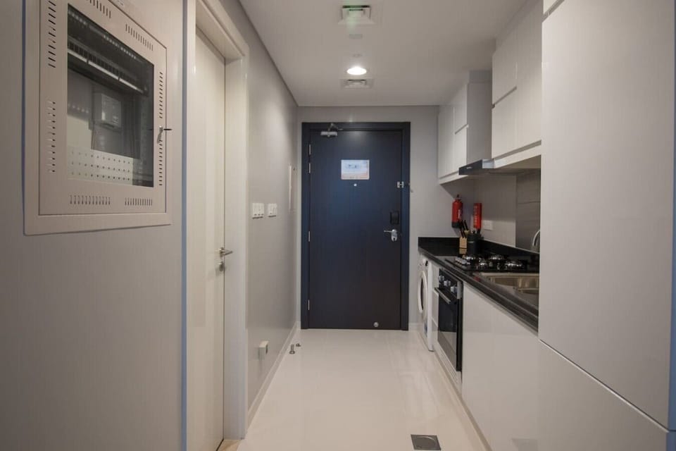 Clean entryway w/ a dark front door & a glimpse into the open kitchen beyond.