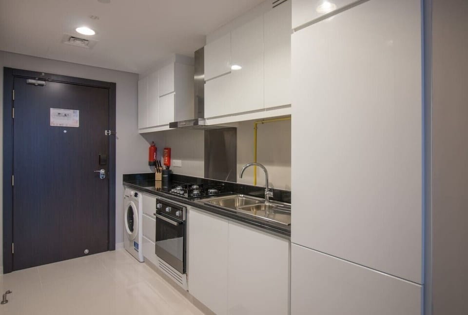 Sleek kitchen w/ dark cabinetry, stainless steel appliances, & ample prep space for cooking in.