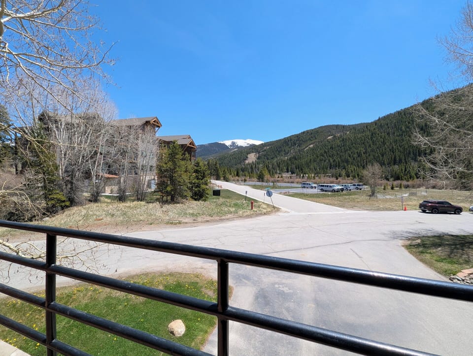 Mountain vistas frame the property entrance, offering scenic surroundings with forested hillsides and snow-capped peaks visible from the area. A quiet neighborhood setting provides a peaceful mountain retreat atmosphere.