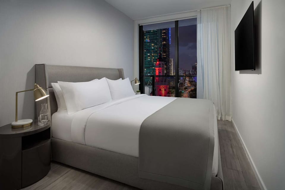 Unwind in crisp linens with sparkling city lights outside.