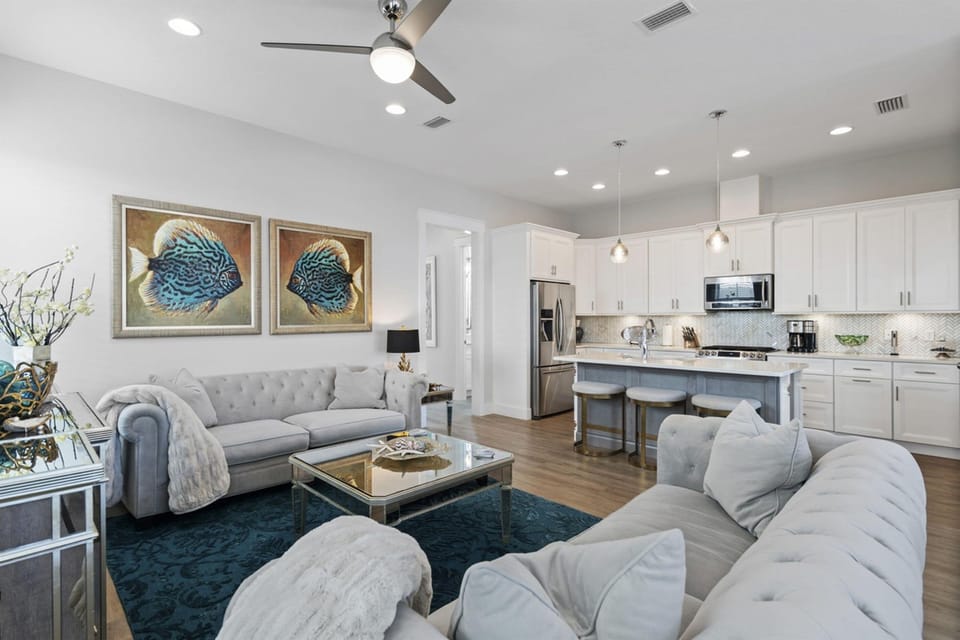 Settle into your elegant open-concept living space where coastal charm meets modern comfort, featuring plush seating and a fully-equipped kitchen perfect for your stay.