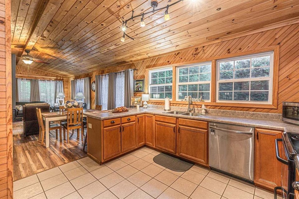 Kitchen view featuring sink, cabinets, and natural wood walls.