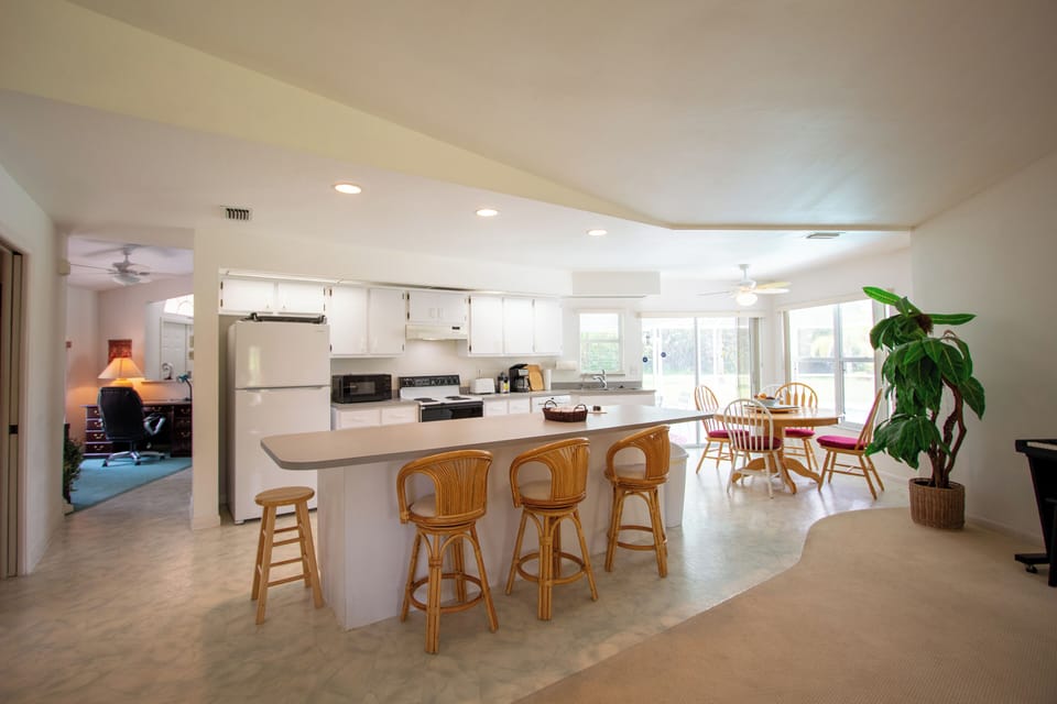 Kitchen island with 3 chairs next to the breakfast/dining area seating 4