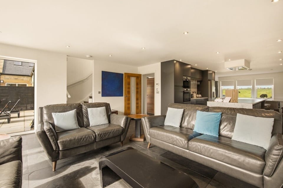 Open-plan lounge with leather sofas and modern kitchen beyond