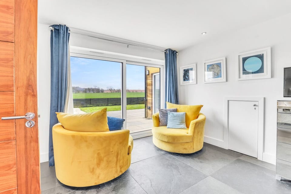 Yellow velvet chairs beside floor-to-ceiling countryside views