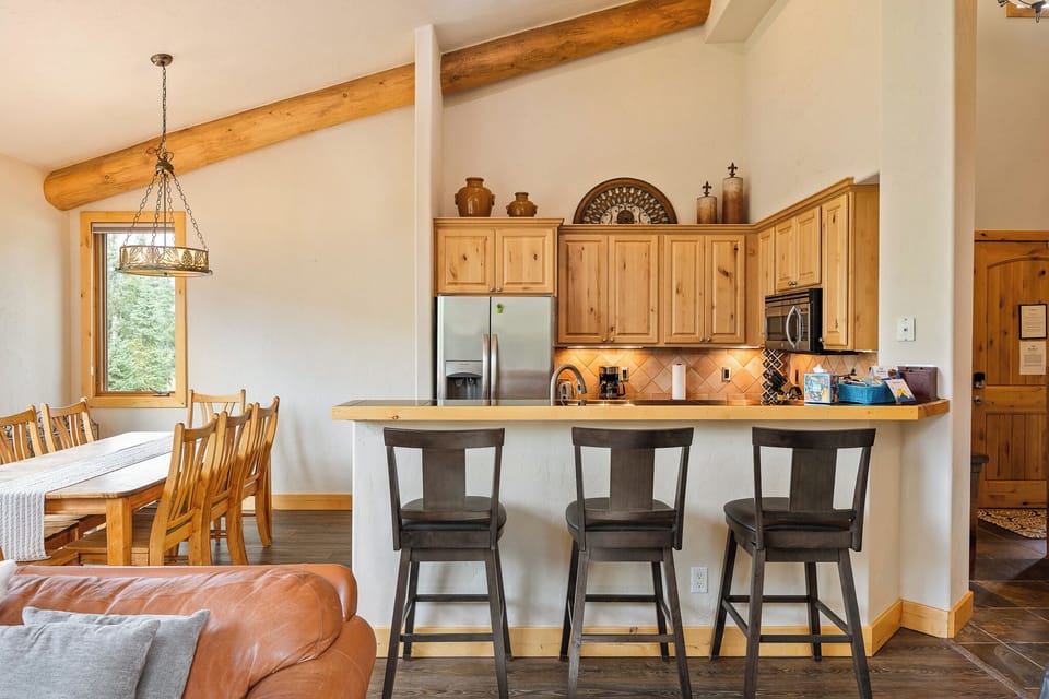 Breakfast bar with seating beside fully equipped kitchen   - Rustic wood cabinets and modern appliances provide ease   - Great space for casual dining or morning coffee indoors