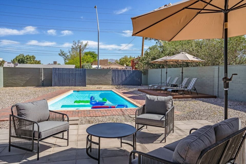 Sun-soaked backyard w/ sparkling pool, comfy lounge seating & shaded dining for relaxed desert afternoons.