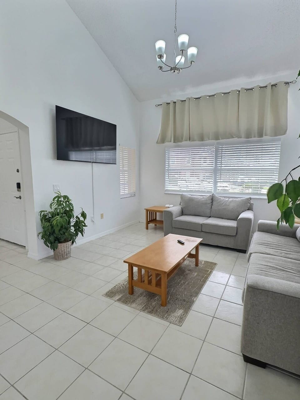 Step into a bright living room featuring ample natural light streaming through elegant window treatments. The cozy gray sofa invites relaxation, while the wooden coffee table adds a warm, homey touch to this inviting space.