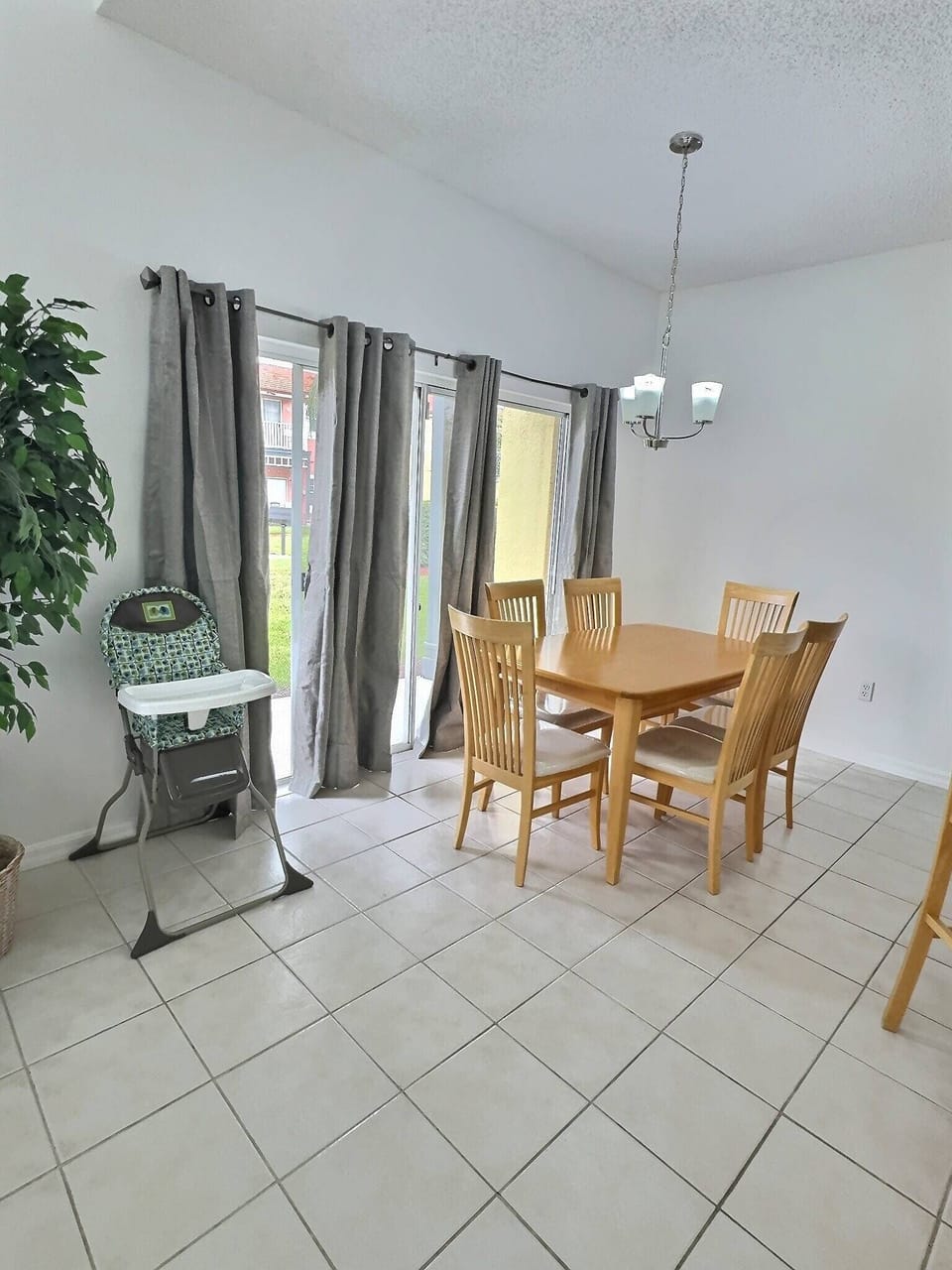 Bright and airy, this dining area features a sleek wooden table surrounded by comfortable chairs, perfect for shared meals. Natural light floods in through large glass doors, enhancing the cheerful ambiance of your stay.