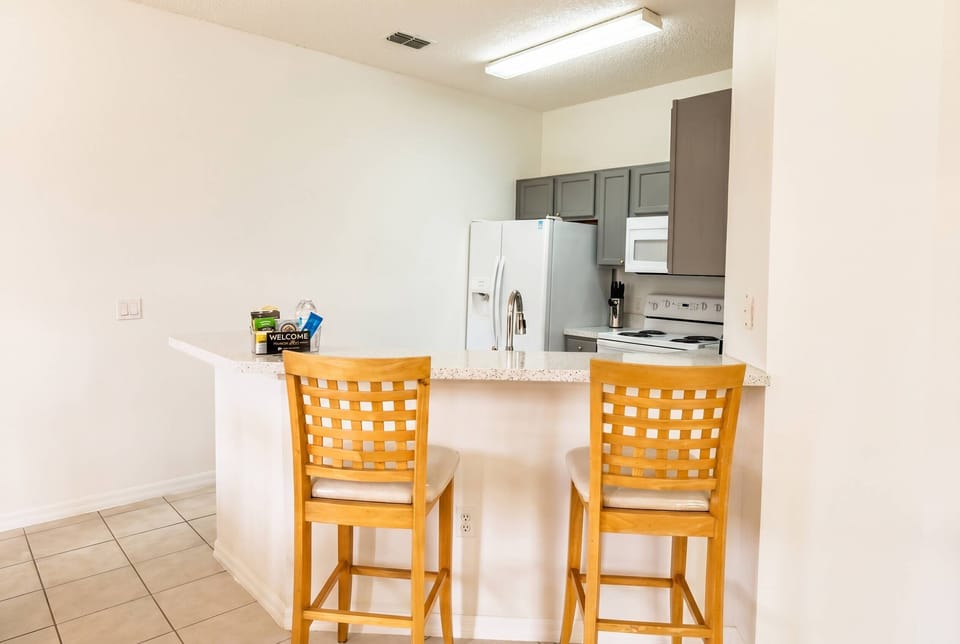 Savor casual dining at the stylish breakfast bar with light wood stools. The bright, open kitchen boasts modern appliances and plenty of counter space, creating a warm atmosphere for guests to enjoy meals and moments together.