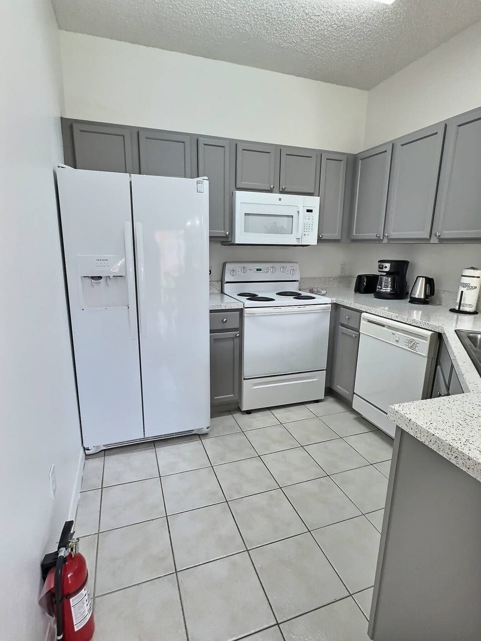 Discover the inviting kitchen with sleek gray cabinets and ample countertop space, perfect for meal prep. Equipped with modern appliances like a refrigerator and microwave, it's an ideal setting to easily create your favorite.