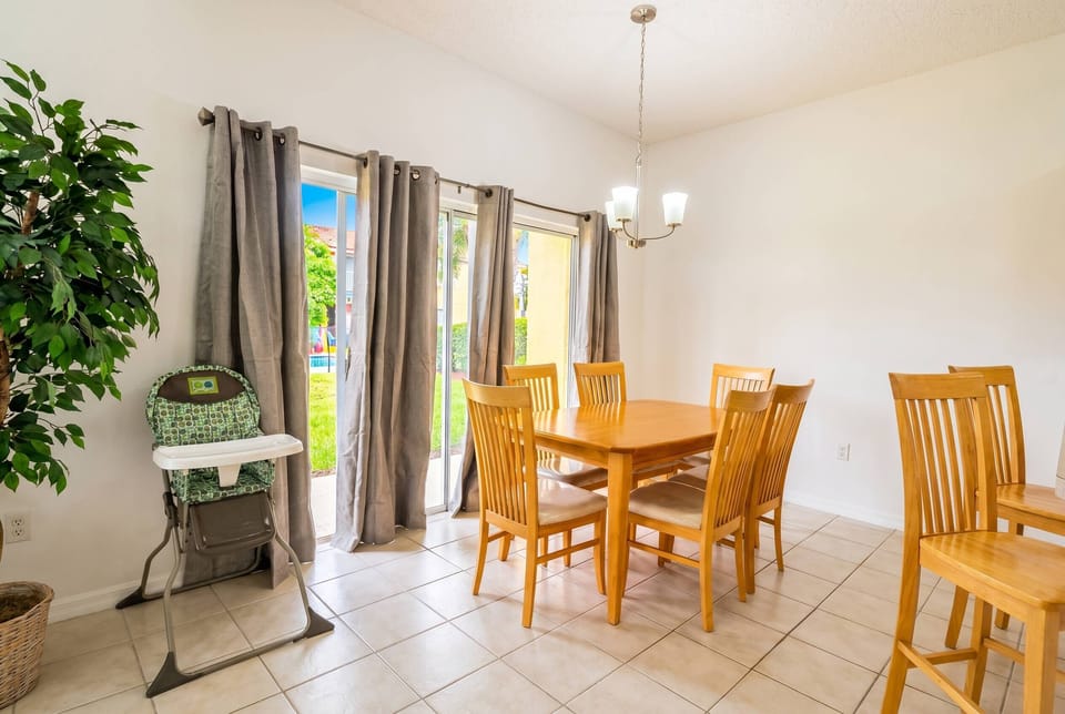 Bright and airy, this dining area features a sleek wooden table surrounded by comfortable chairs, perfect for shared meals. Natural light floods in through large glass doors, enhancing the cheerful ambiance of your stay.
