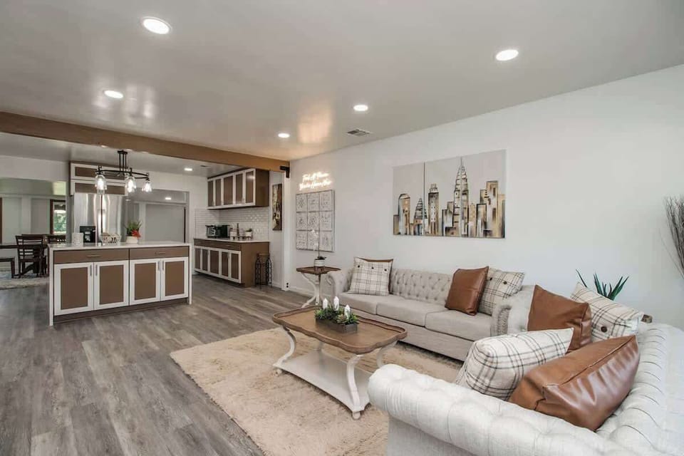 Settle into the open living area with plush seating, a soft rug, and skyline wall art—perfect for slow mornings at the coffee table while the kitchen stays in view.