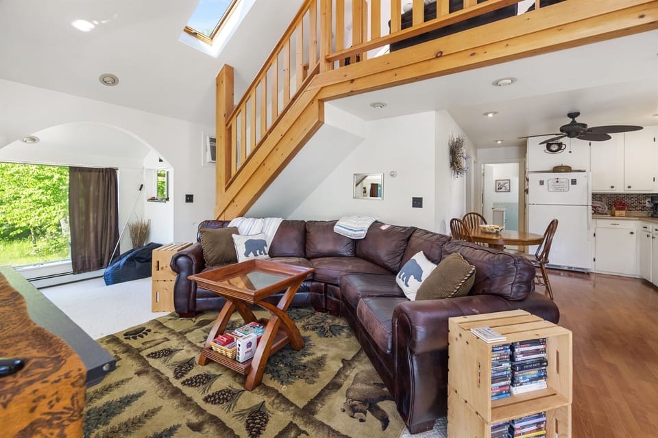 second living room with leather couch and stairs in the background