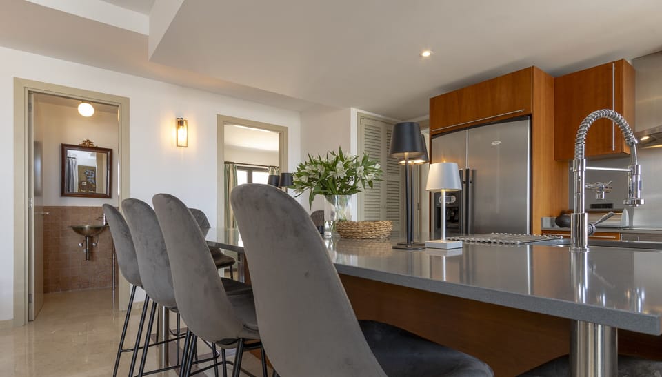 Modern kitchen with a spacious breakfast bar and high stools, connected to the living areas and featuring a guest toilet accessible from the room.