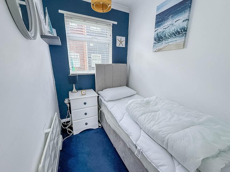 Cozy single bedroom with bright window and calming blue accents