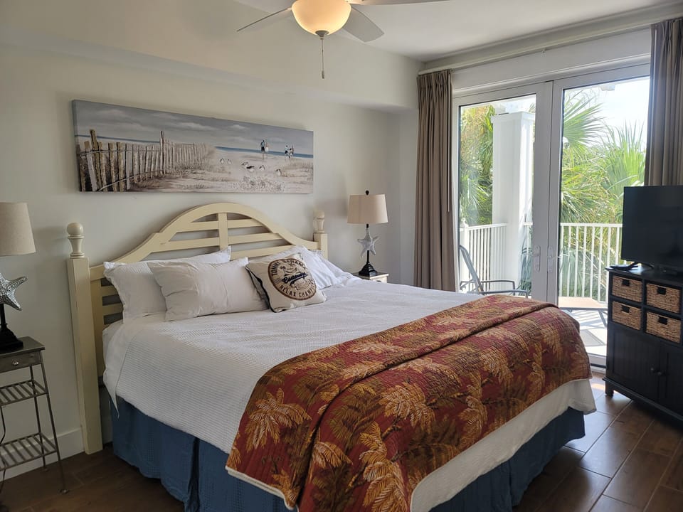 Bedroom with king bed, smart TV, and ceiling fan, with access to private balcony