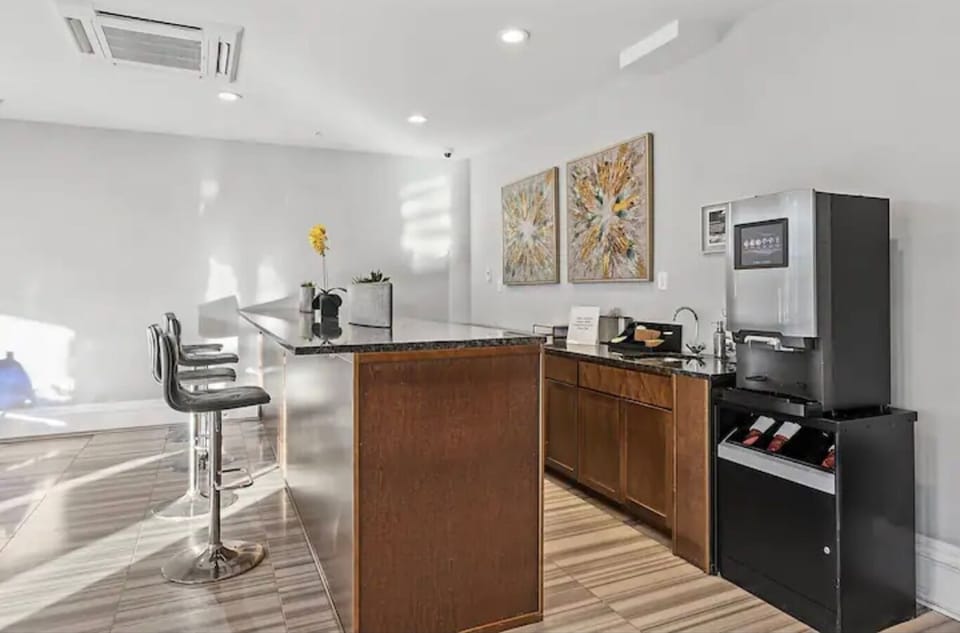 Common lounge with breakfast bar, espresso machine, and modern cabinetry providing convenient shared gathering space.