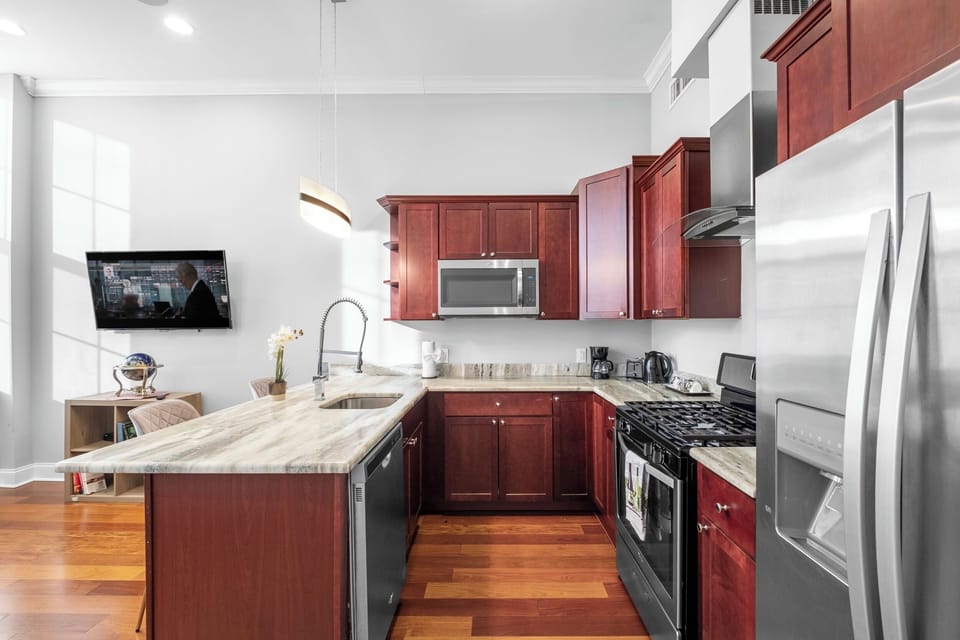 Fully-equipped kitchen with cherry wood cabinets, stainless appliances, and granite counters ideal for preparing home-cooked meals.