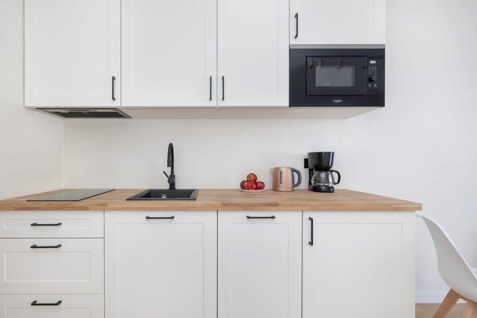 A modern kitchenette with an induction hob, toaster, and dishwasher perfectly fits the functional character of the apartment.