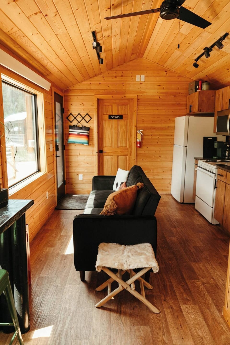 Open concept living room, kitchen and dining room make this tiny cabin feel light and airy. Large picture windows provide gorgeous forested views from the privacy of your cabin in any season!