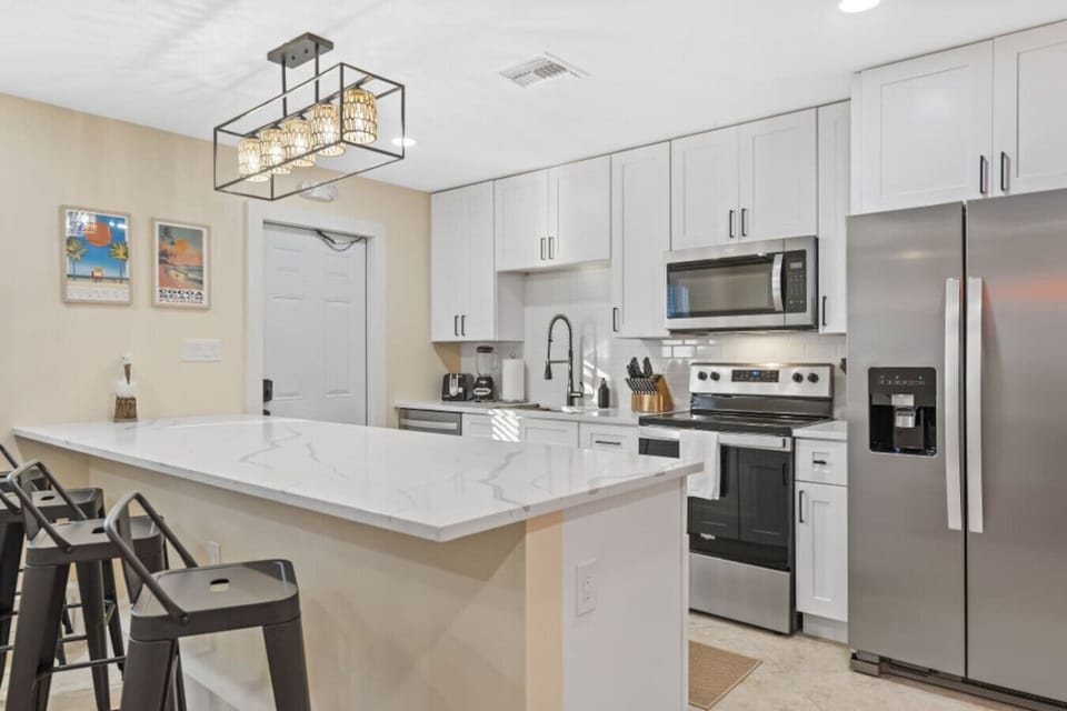 Cocoa Beach Kitchen | Modern waterfall island, statement lighting & chic coastal ambiance