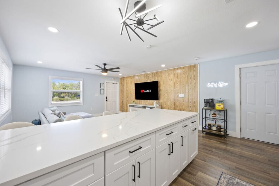 Cocoa Beach Open Living | Airy coastal space with a Smart TV, marble island, and warm wood accents for comfortable gatherings.