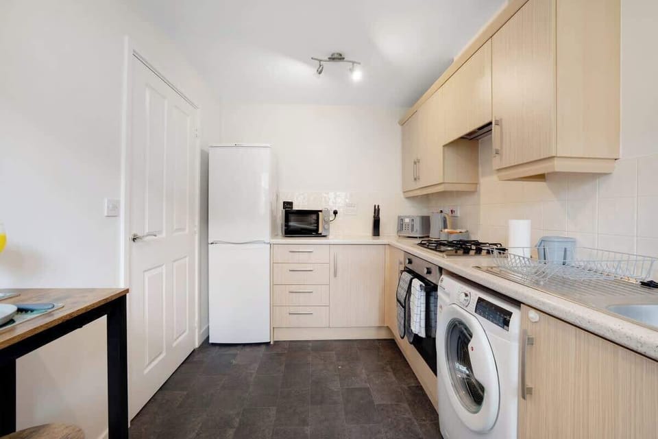 A practical and stylish kitchen offering an oven, fridge, and full cookware set, plus a convenient breakfast counter for two.
