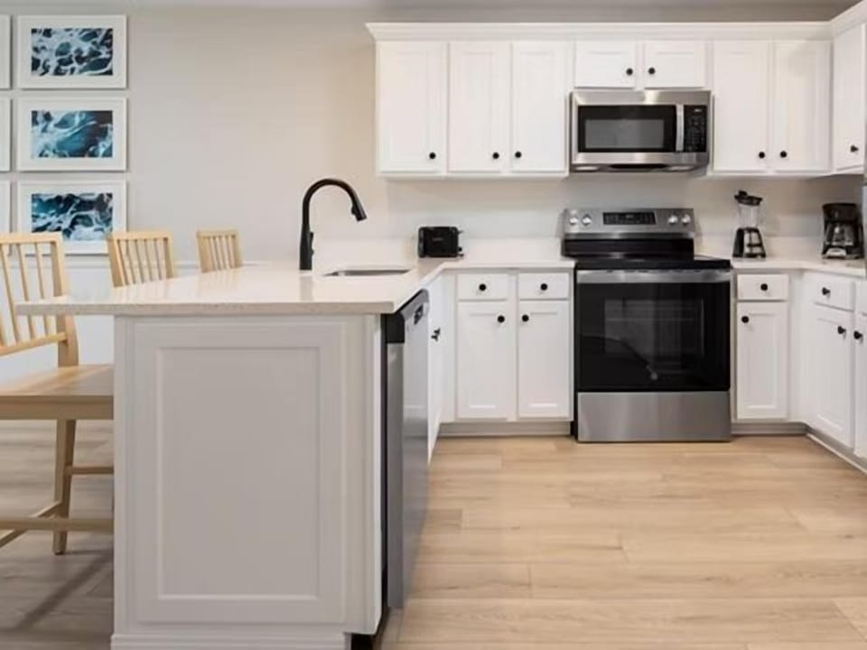 White kitchen with stainless steel appliances, dishwasher, coffee machine, and full counter space