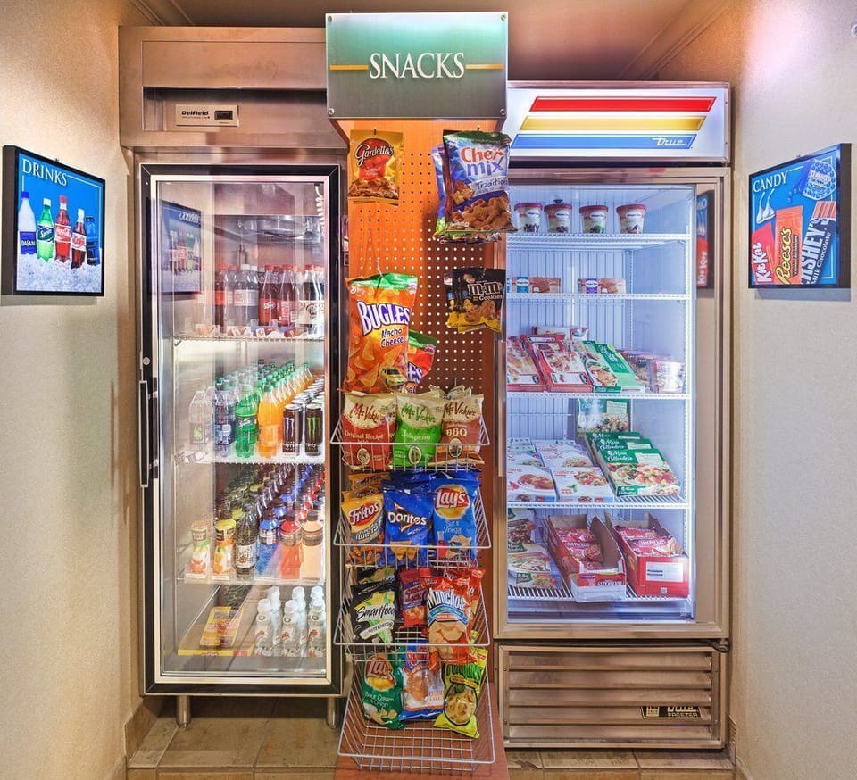 The snack area contains fridges filled with drinks and shelves of assorted snacks for a quick grab-and-go.