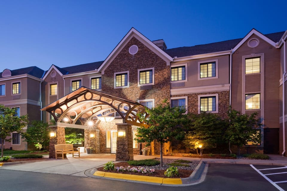 Step into a welcoming entrance framed by warm lighting and lush greenery.