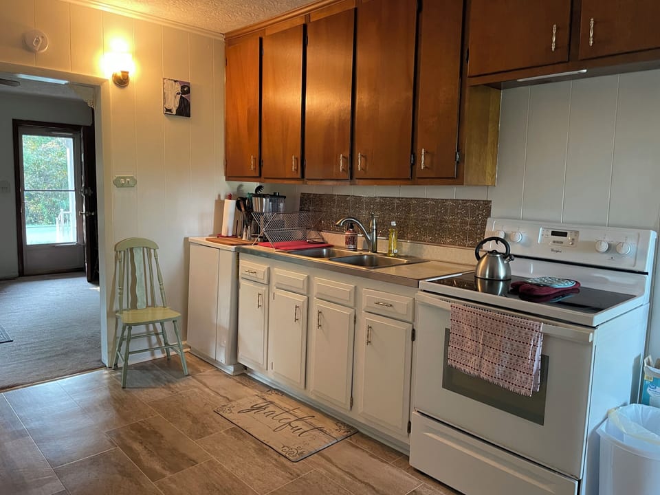 Clean and neat kitchen with complete set of glasses, dishes, pots, pans, etc.