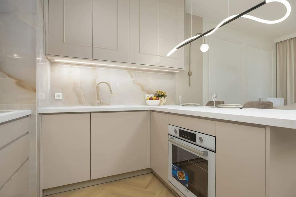 Kitchenette with white countertops, stainless steel appliances, and under-cabinet lighting.