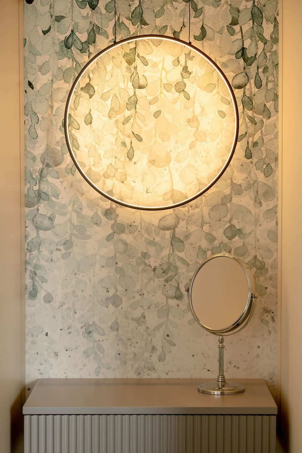 Bedroom with a double bed and an elegant circular light fixture on the wall. 