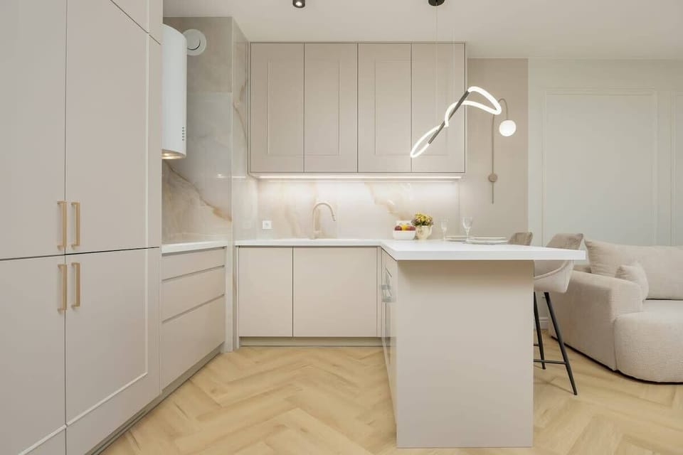 Kitchenette with white cabinetry, minimalist style, and integrated lighting under cabinets.