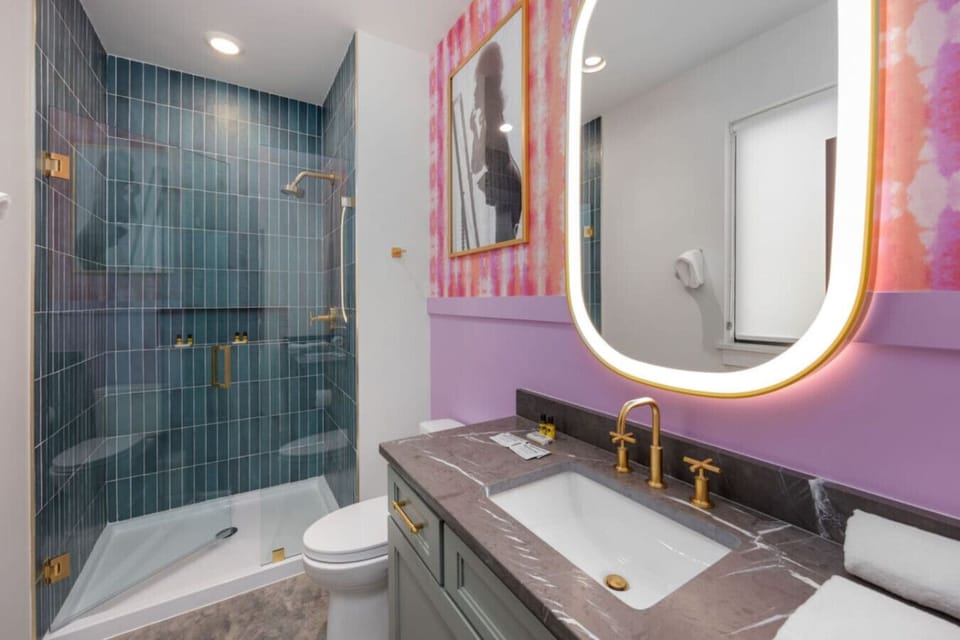 Teal subway tile, a gold faucet, and a backlit mirror make this bathroom a genuinely beautiful place to get ready.