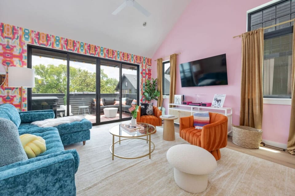 The living room mixes a plush teal sofa with bold orange chairs for a space that feels lively and easy to relax in.