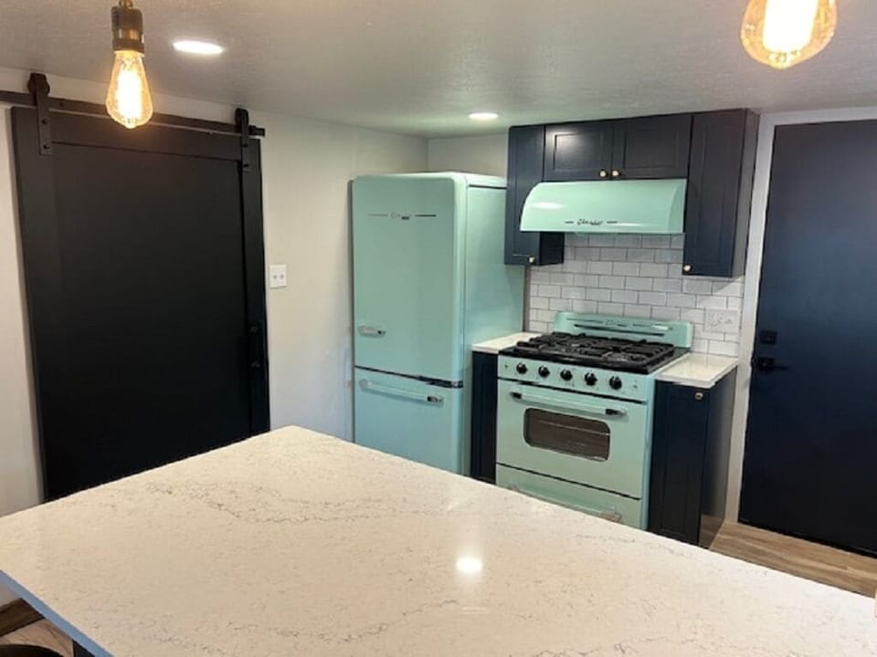 Fridge and stove, sliding barn door to washer/dryer and bathroom area.