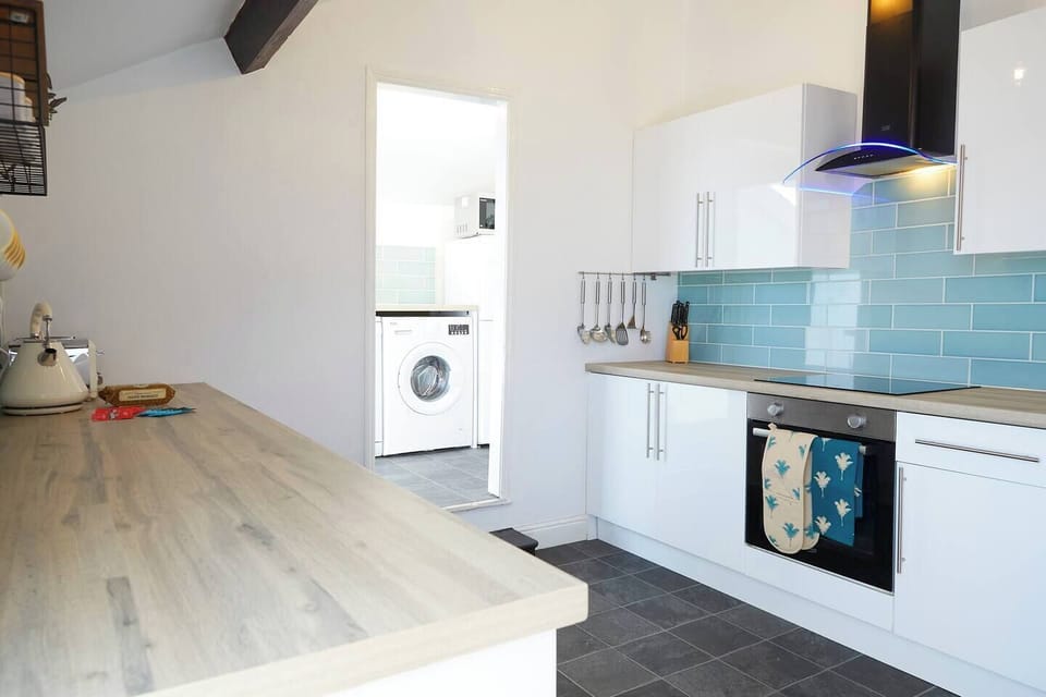 Kitchen and utility. Features sleek cabinetry, pendant lighting, and a stylish backsplash, perfect for cooking and entertaining.
