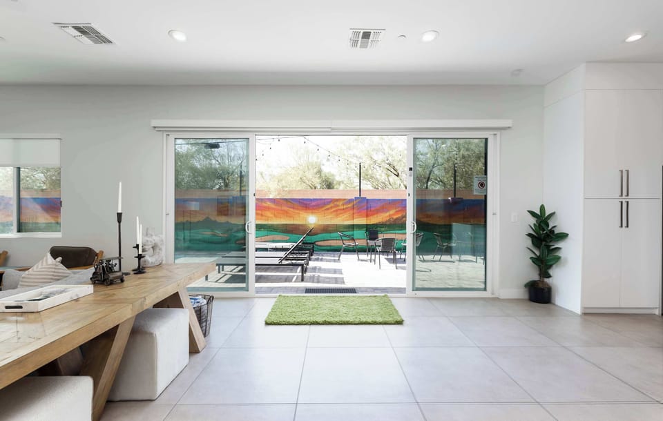 Sliding doors entrance to backyard main patio space with pool chaise loungers, seating, and golf course mural spanning the entire back wall!