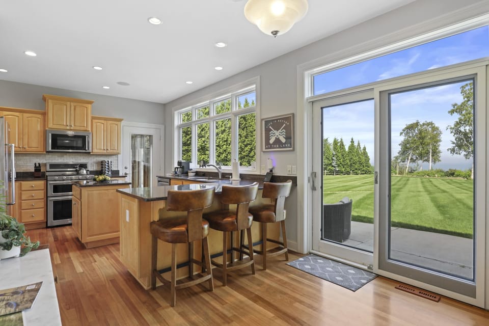 Fully stocked kitchen with island barstool seating, walkout access to the patio and porch, and luxury appliances.