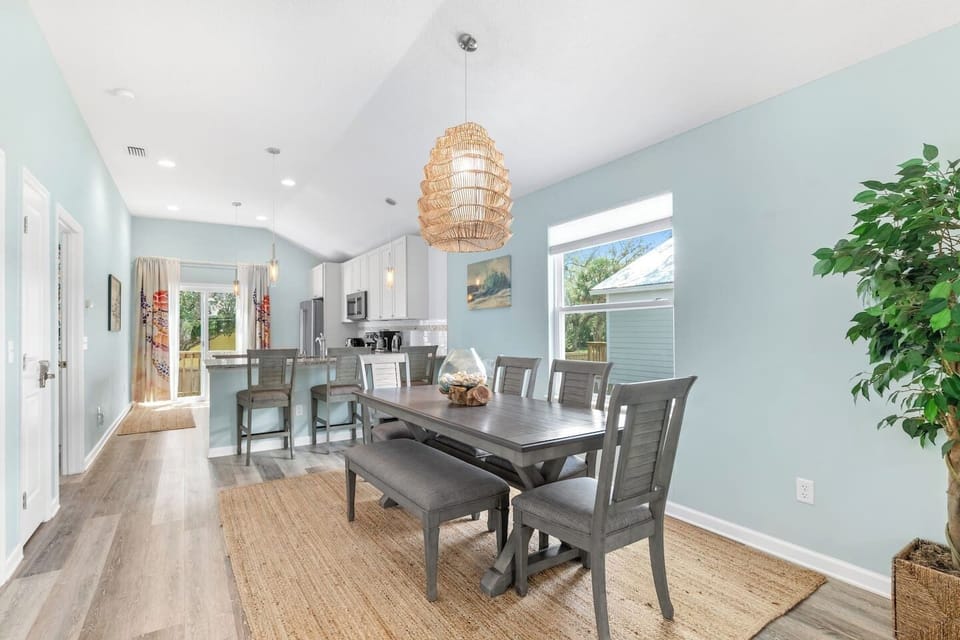 Bright and inviting dining area with a spacious table seating 7 guests, complemented by 3 stylish bar stools for extra seating.