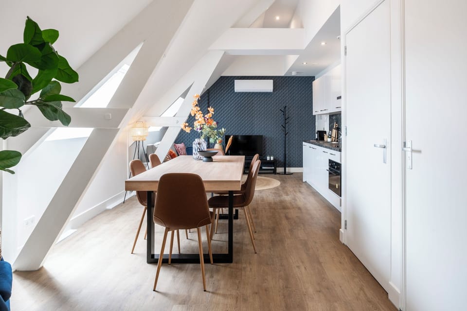A lively dining area under sloped ceilings with modern kitchen amenities in the background, perfect for family meals and social gatherings.