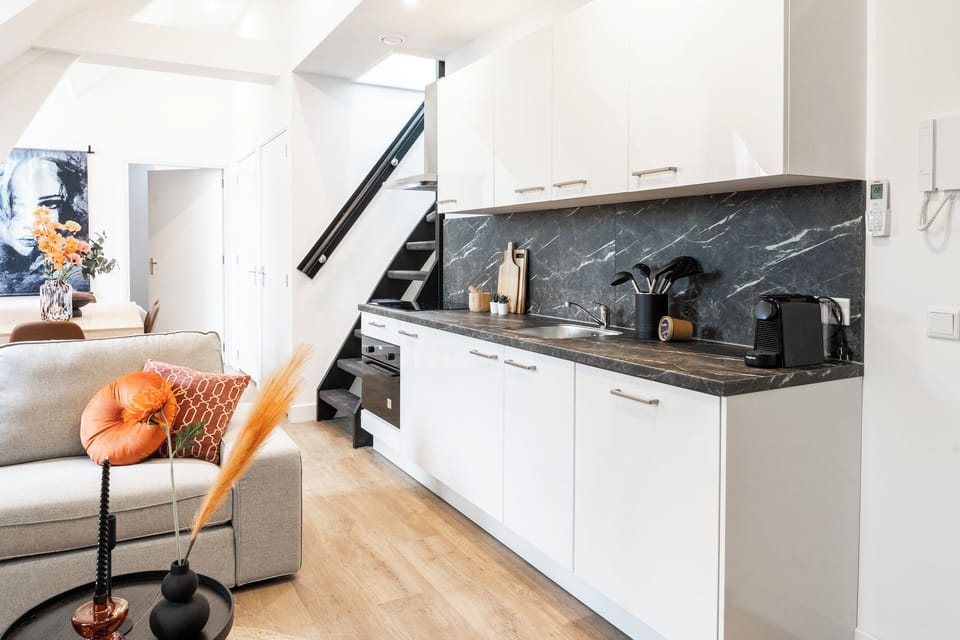 The kitchen is strategically placed next to the sofa or living area, making it easy to transition from cooking to relaxing, perfect for entertaining or casual living.