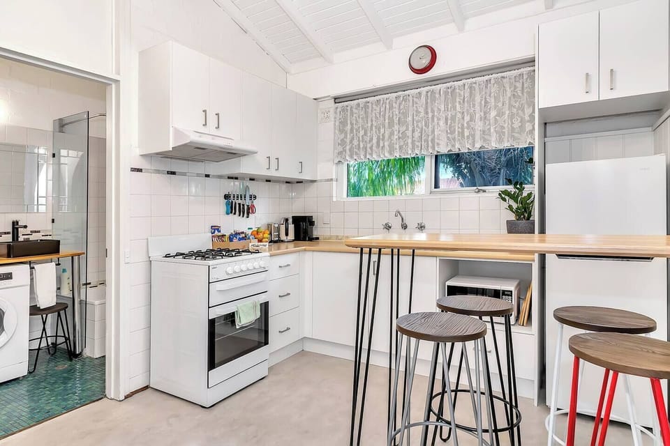 Gather around the kitchen bench with bar stools, serving as a cosy dining area where you can enjoy meals and cocktails at home.