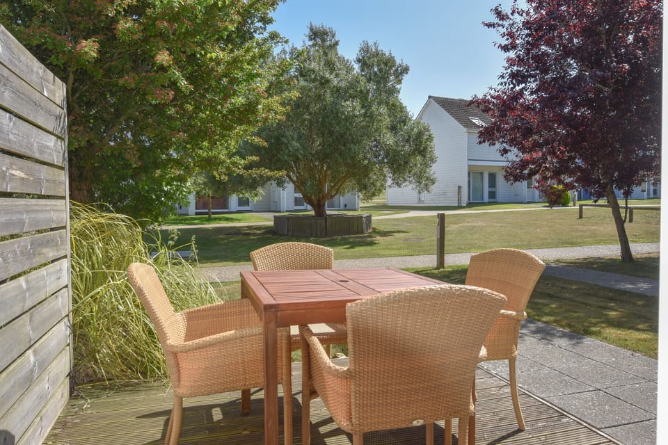 The front decked terrace features a dining set for four, ideal for morning coffee or alfresco holiday meals.